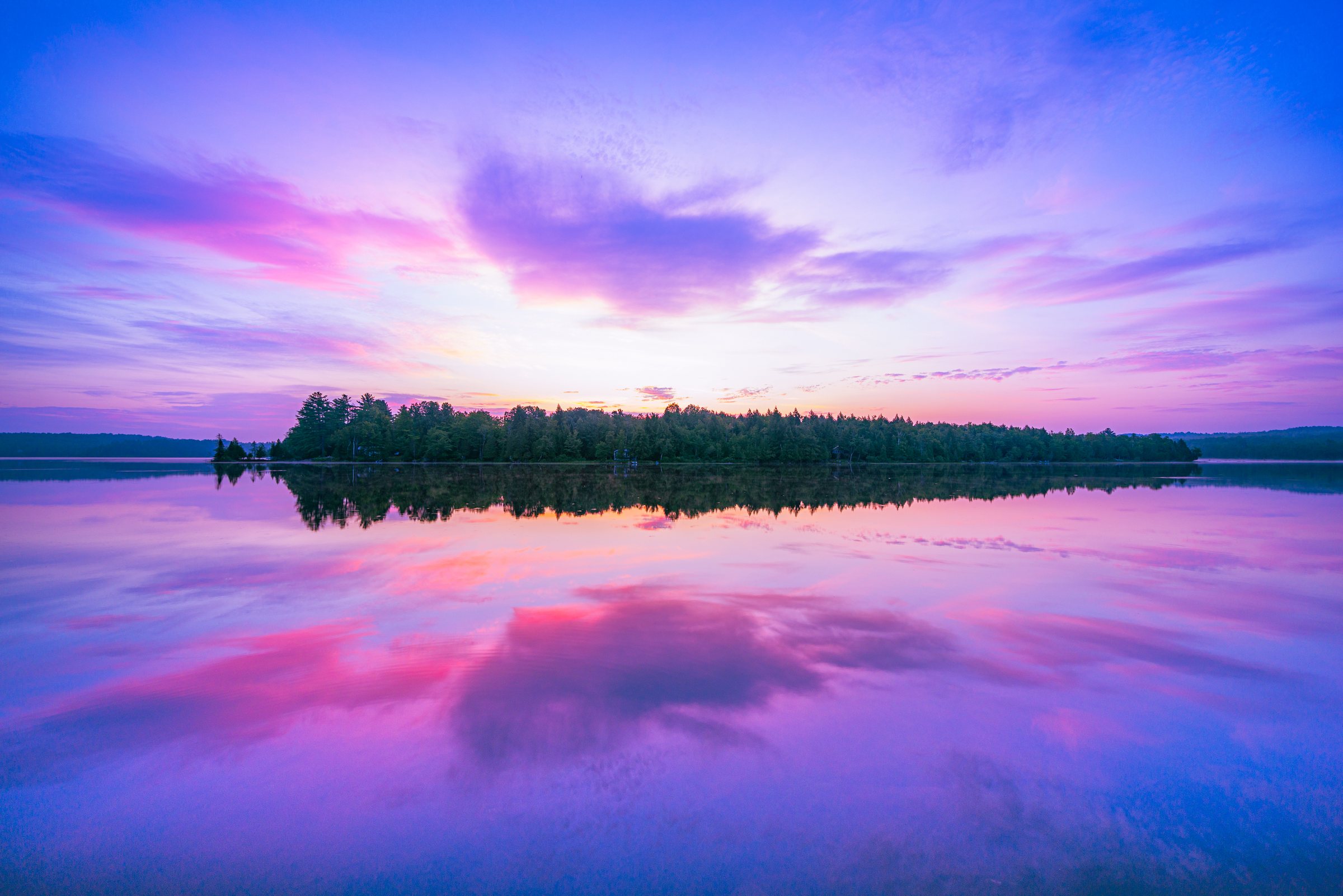 Dragonwood property at dusk with solar-powered lights glowing, Manhanock Pond in background